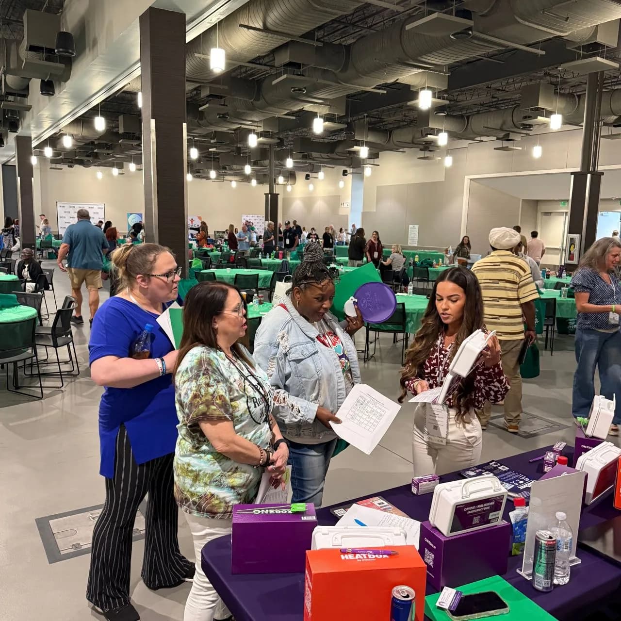 Attendees examining ONEbox® and HEATbox™ kits at a community expo table